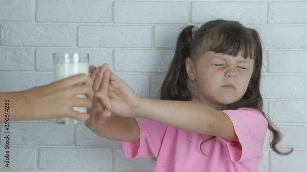 Milk allergy. Lactose intolerance. The little girl refuses a glass of ...