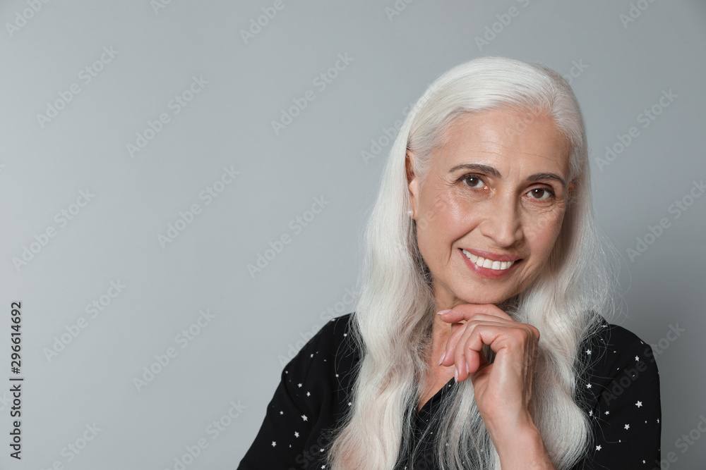 Portrait of beautiful mature woman on grey background, space for text Portrait of beautiful mature woman on grey background, space for text