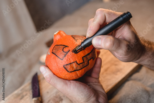 Drawing a face contour marker on a pumpkin to cut a pumpkin head for Halloween
