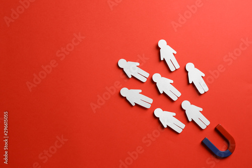 Magnet attracting paper people on red background, flat lay. Space for text photo