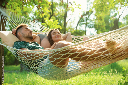 Young couple resting in comfortable hammock at green garden photo
