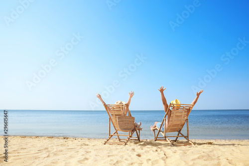 Canvastavla Young couple relaxing in deck chairs on beach