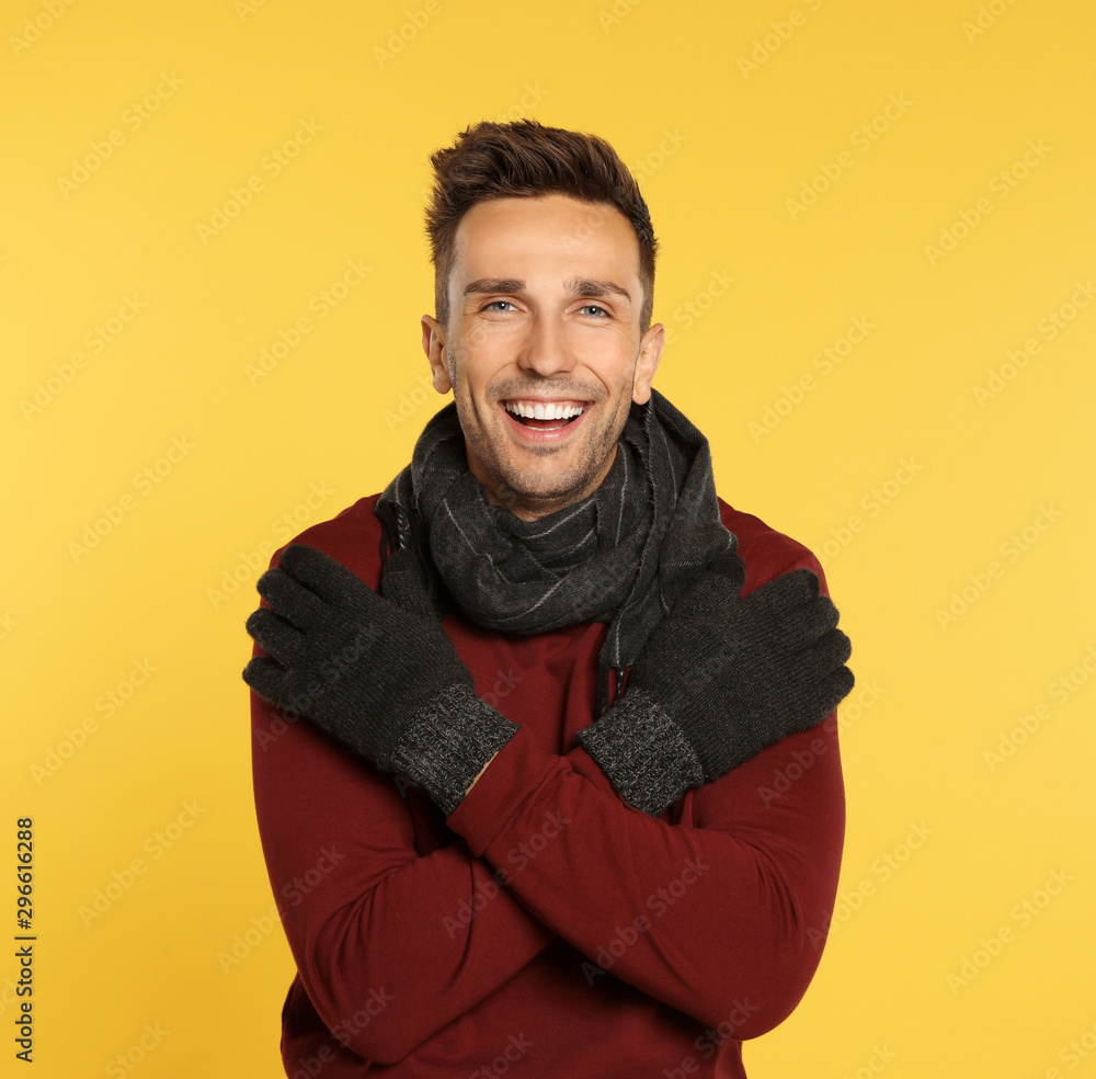 Happy young man in warm clothes on yellow background. Winter season Happy young man in warm clothes on yellow background. Winter season
