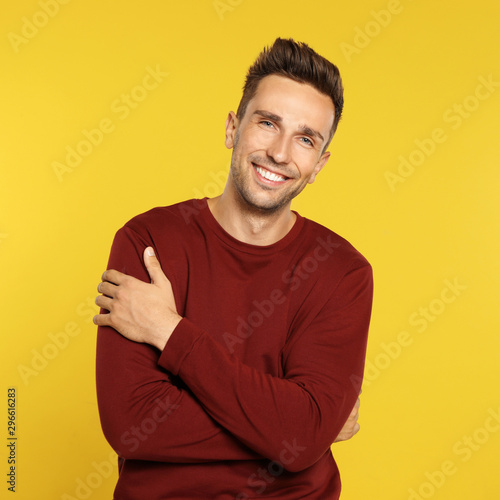 Happy young man in sweatshirt on yellow background. Winter season © New Africa