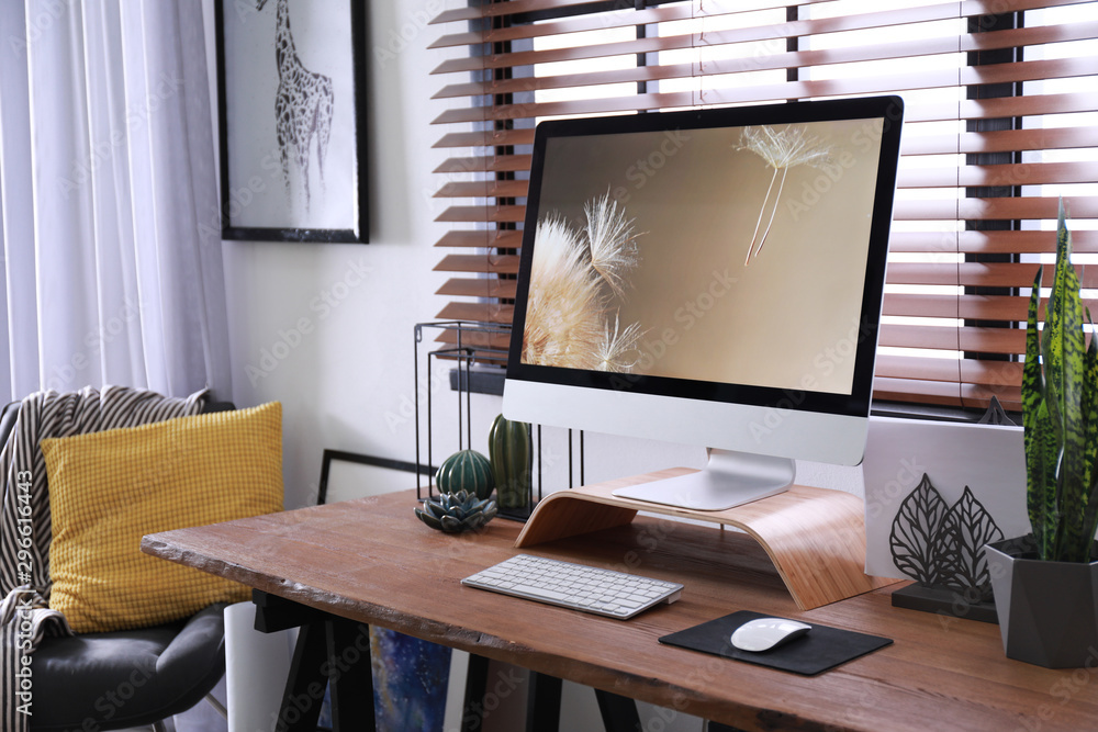 Fototapeta premium Comfortable workplace near window with horizontal blinds in room