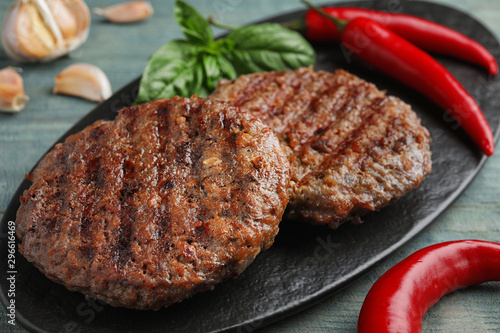 Cuadro en lienzo Grilled meat cutlets for burger on blue wooden table, closeup
