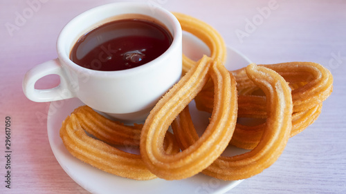 Churros con chocolate caliente, a traditional Spanish street food, a sweet treat consisting of a cup of thick hot chocolate drink and crispy, long and curly fried-dough pastry served aside for dipping