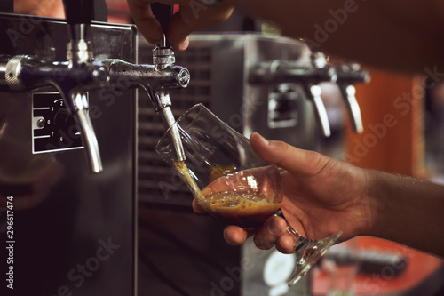 Bartender pouring beer into glass in pub  closeup