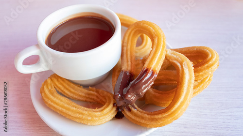 Churros con chocolate caliente, a traditional Spanish street food, a sweet treat consisting of a cup of thick hot chocolate drink and crispy, long and curly fried-dough pastry served aside for dipping