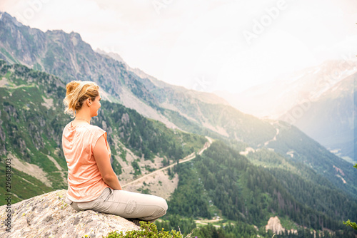 Woman sitting on a rock on top of the hill, watching panorama