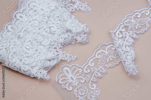 Fototapeta Naklejka Na Ścianę i Meble -  Texture lace fabric. lace on white background studio. thin fabric made of yarn or thread. a background image of ivory-colored lace cloth. White lace on beige background.