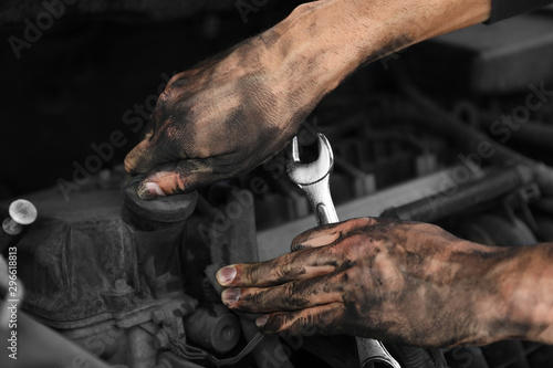 Dirty mechanic fixing car, closeup of hands