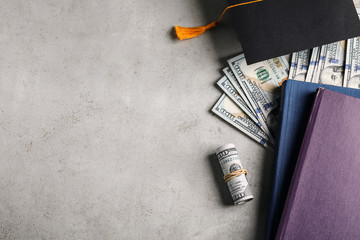 Flat lay composition with dollars and student graduation hat on stone background, space for text. Tuition fees concept