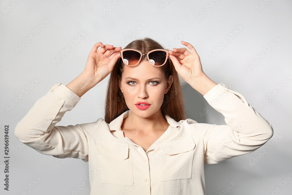 Young woman wearing stylish sunglasses on light background Young woman wearing stylish sunglasses on light background