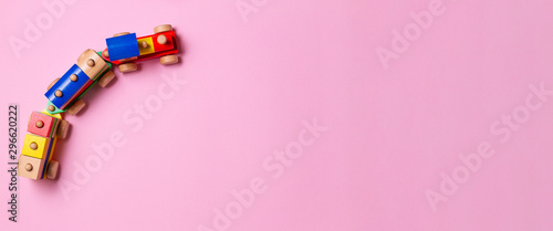Wooden toy train with colorful blocks on light pink background