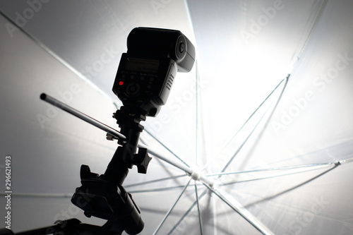 Camera flash flashes in a white umbrella in the photography studio. © N. Rotteveel