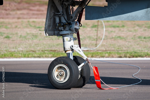 Landing gear closeup from an aircraft on the ground by daylight with red safety label attached.