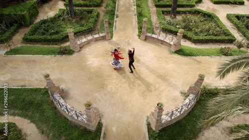 Aerial view from drone of man and woman dancing flamenco in park. Spanish people and traditional dance in Andalusia, Spain. Dancers performing traditional show in park. Couple and music arts