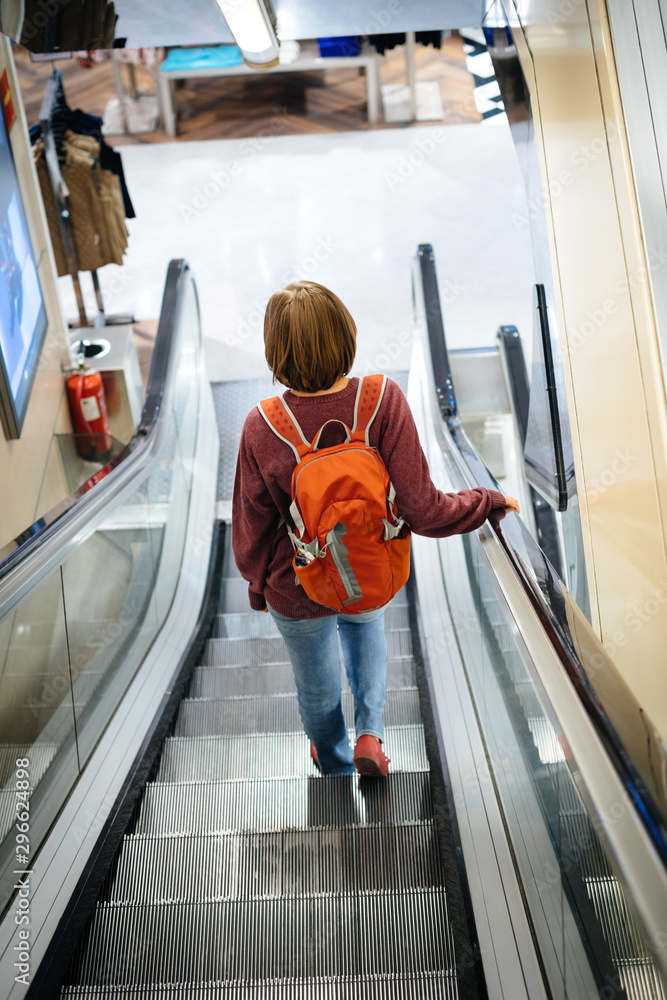 custom made wallpaper toronto digitalRear view of elegant single woman with red backpack descending escalator in large commercial department store