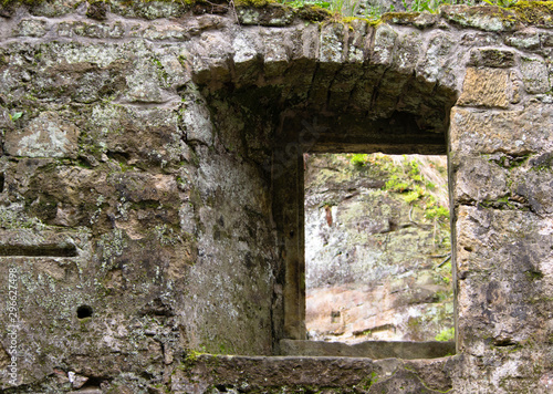 Fototapeta Naklejka Na Ścianę i Meble -  view through a window in the wall of the ruins of an old water mill made of natural stone in the forest near Dolny Mlyn in Bohemian Switzerland national park