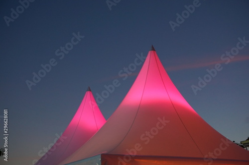 pink  lighted top of easy up tents at dusk