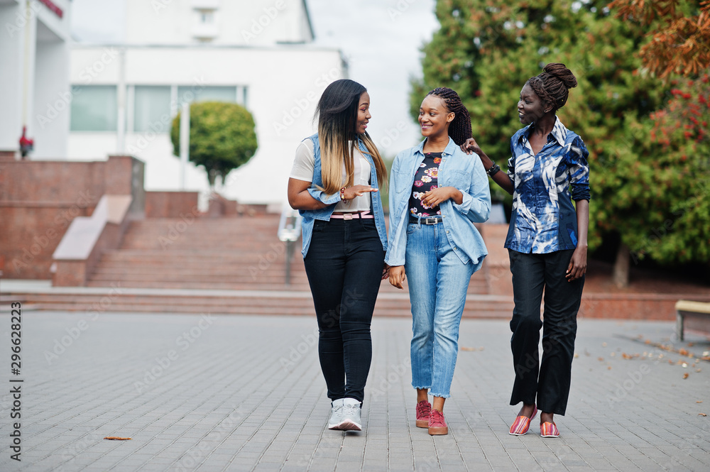 Obraz premium Group of young black female friends hanging out in the city. Multiracial african women walking by the street and discuss.