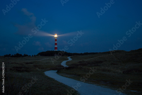 lighthouse of Ameland at night with light beaming across the deep blue sky