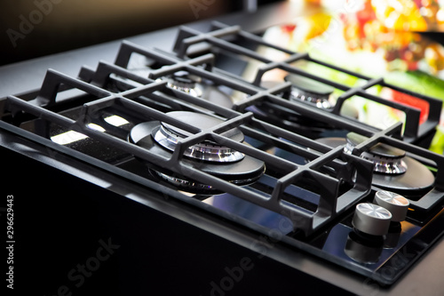 New modern gas stove with four burners for the kitchen, stainless steel surface. Cast iron grates. yellow background in blur photo