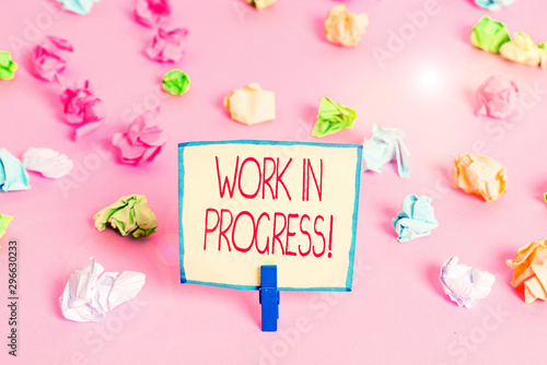Text sign showing Work In Progress. Business photo text unfinished project that still added to or developed Colored crumpled papers empty reminder pink floor background clothespin