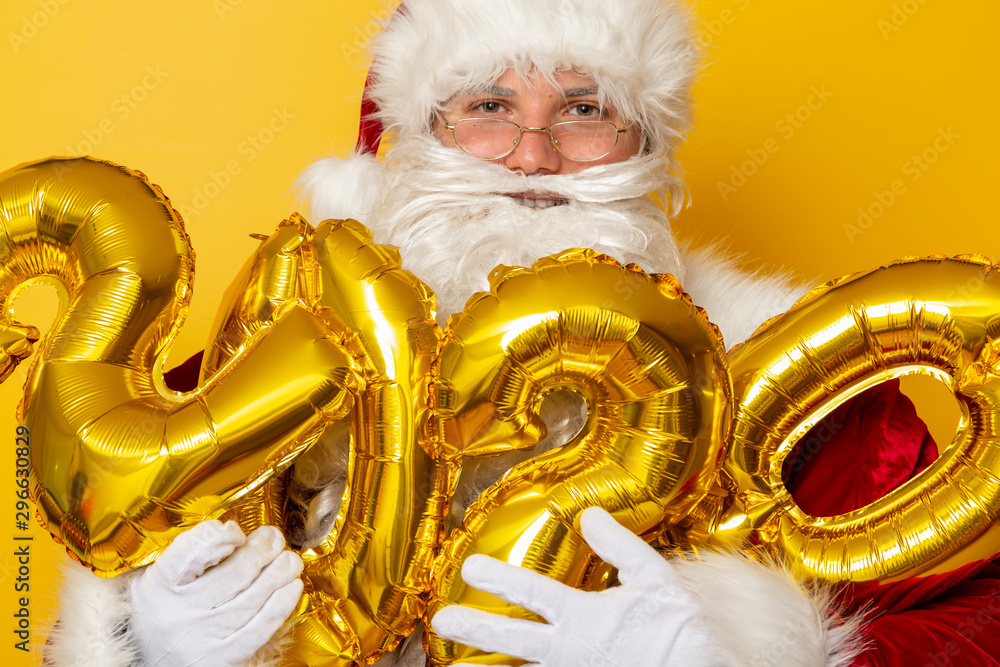 Santa Claus holding golden 2020 balloons