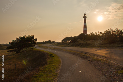 Sunrise behind vuurtoren, the lighthouse of Ameland, with street leading towards the building