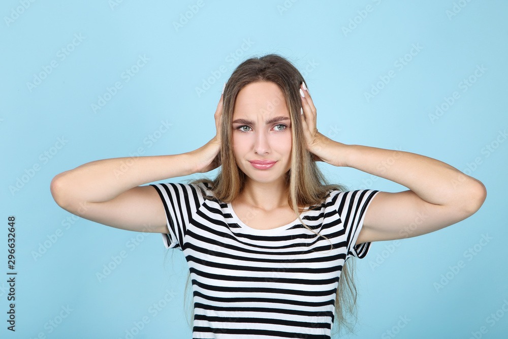 Beautiful young woman closing ears by hands on blue background Beautiful young woman closing ears by hands on blue background