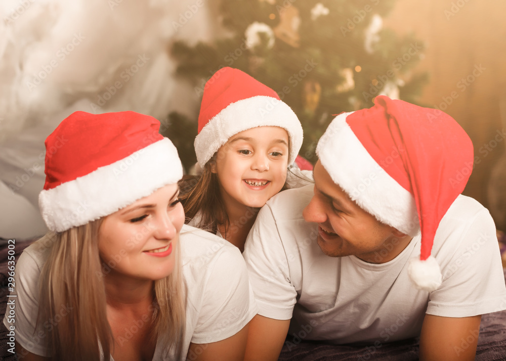 Portrait of friendly family in Santa caps looking at camera on Christmas evening Portrait of friendly family in Santa caps looking at camera on Christmas evening