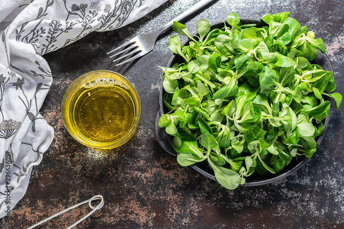 Fotografija Lamb lettuce or corn salad with olive oil on the table