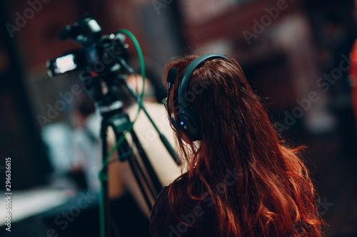 Young woman operator in headphones and with a video camera