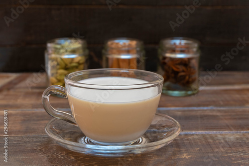 Warm indian drink with spices masala chai on brown wooden background