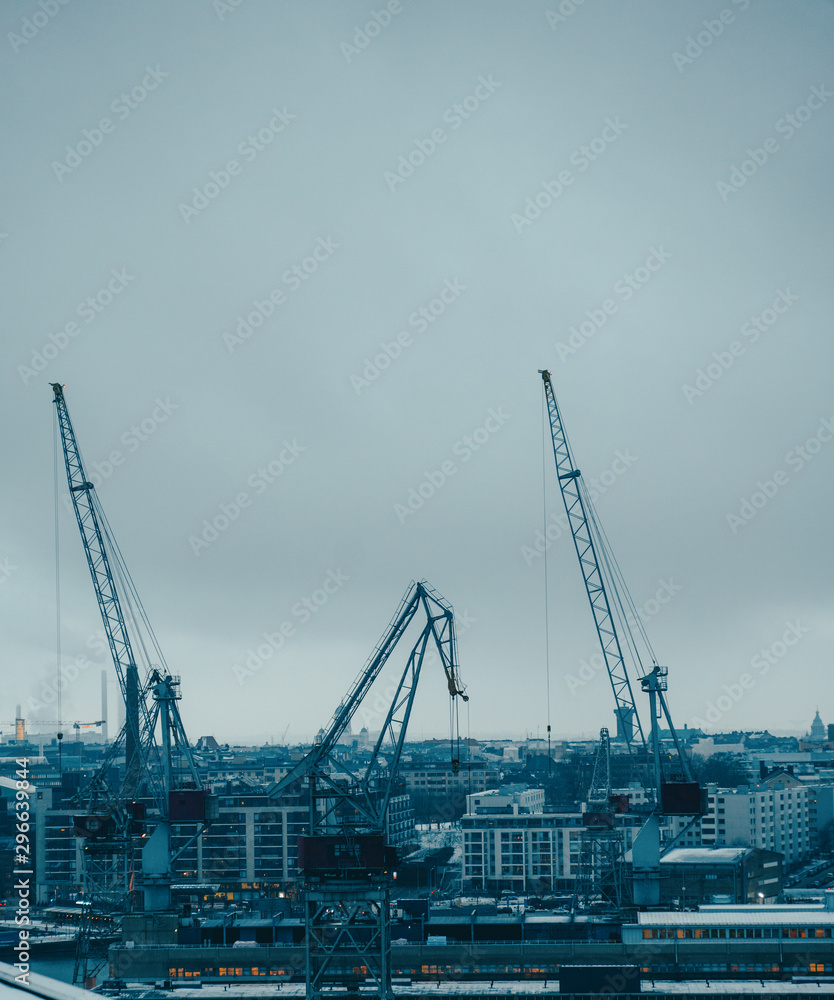 Image of river, floating cranes, buildings on river bank.