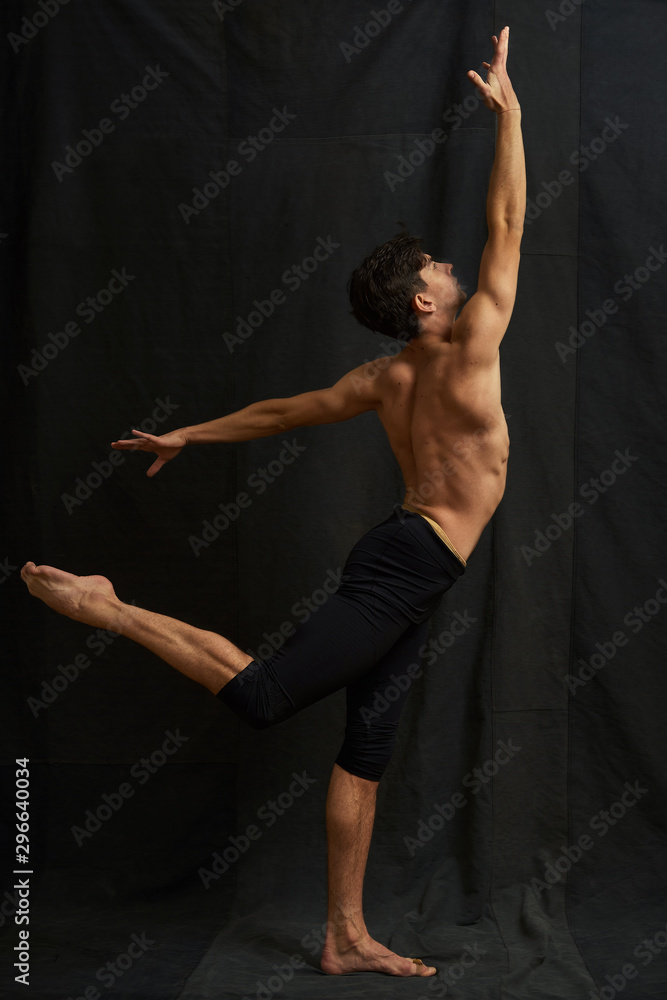 Young studio ballet dancer is dancing. A man is photographed from the back.
