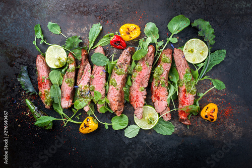 Barbecue wagyu hanging tender steak with chili, lettuce and chimichurri sauce as top view on a rustic board photo