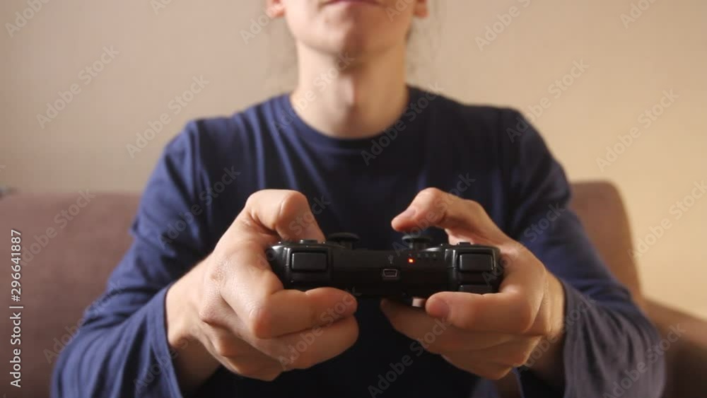 Closeup of man's hands playing video games on gaming console sitting on the couch Closeup of man's hands playing video games on gaming console sitting on the couch