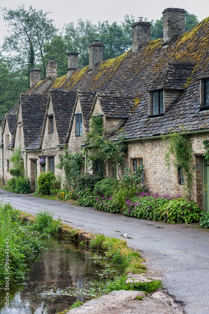 BIBURY, COTSWOLDS, UK - MAY 28, 2018: Traditional cotswold stone cottages built of distinctive yellow limestone in the world famous Arlington Row, Bibury, Gloucestershire, England BIBURY, COTSWOLDS, UK - MAY 28, 2018: Traditional cotswold stone cottages built of distinctive yellow limestone in the world famous Arlington Row, Bibury, Gloucestershire, England