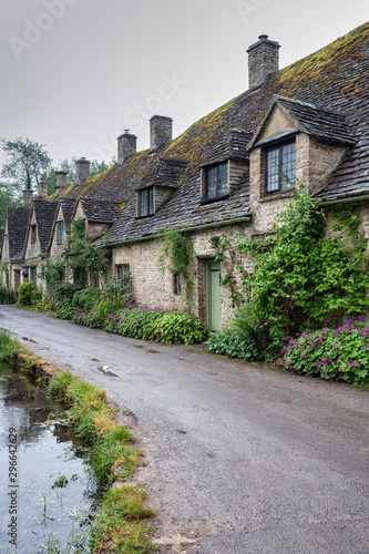 BIBURY, COTSWOLDS, UK - MAY 28, 2018: Traditional cotswold stone cottages built of distinctive yellow limestone in the world famous Arlington Row, Bibury, Gloucestershire, England 