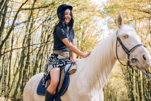 beautiful young girl riding a horse in the autumn forest