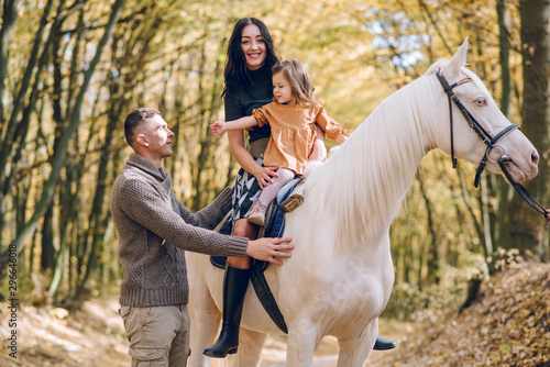 Young family is learning to ride a beautiful white horse in the autumn forest. Riding lesson © Олег Кошевський