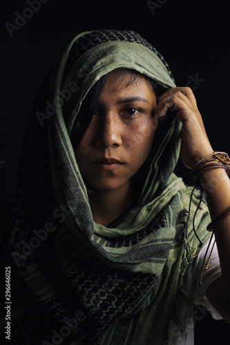woman with freckles on the face Wearing a headdress and scarf with ornaments made of leather and rings On a black background and shadows
