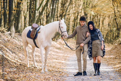 Beautiful young couple walking in the autumn forest. Horseback riding in the autumn forest.