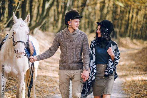 Beautiful young couple walking in the autumn forest. Horseback riding in the autumn forest.