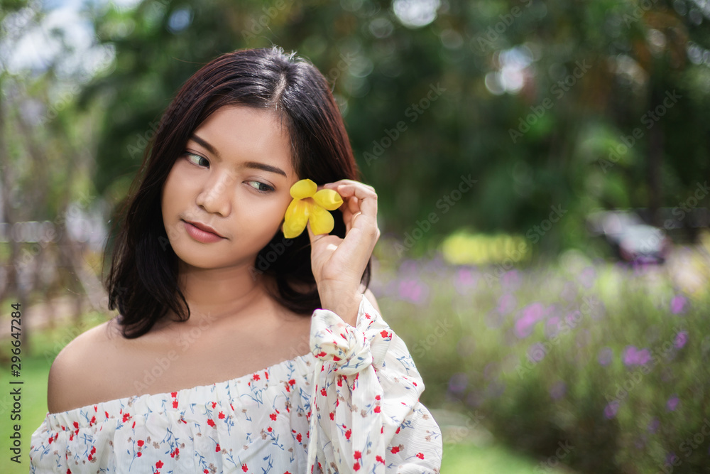 Beautiful asian short hair girl with perfect tan skin smile happily She used the yellow flowers to tuck at her ear, The beautiful face of a Thai woman. Beautiful asian short hair girl with perfect tan skin smile happily She used the yellow flowers to tuck at her ear, The beautiful face of a Thai woman.