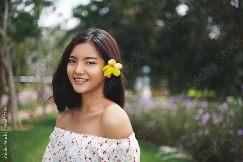 Beautiful asian short hair girl with perfect tan skin smile happily She used the yellow flowers to tuck at her ear,  The beautiful face of a Thai woman.