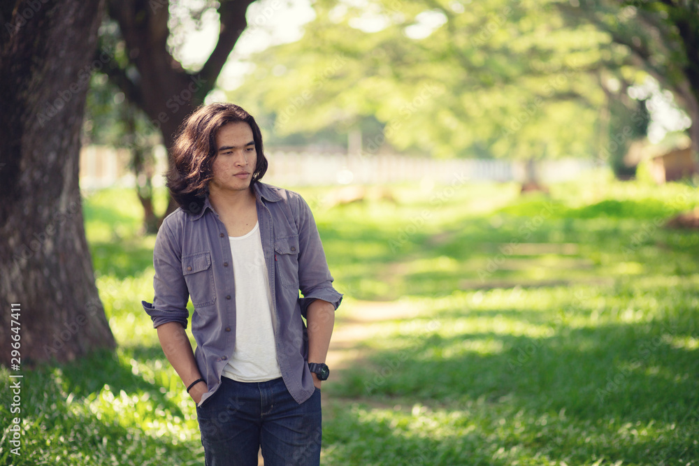 Asian long hair man Walking in the garden The background is a tree and the sunlight in autumn. Asian long hair man Walking in the garden The background is a tree and the sunlight in autumn.